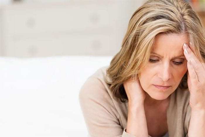 woman holding hand to head, looking distressed