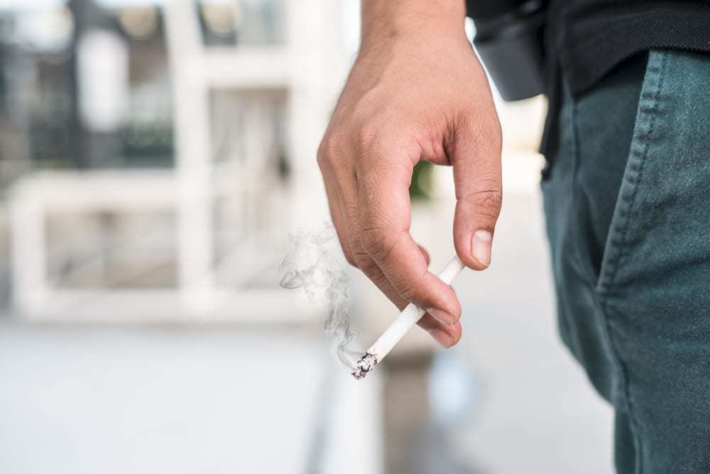 close-up of man's hand holding a smoking cigarette