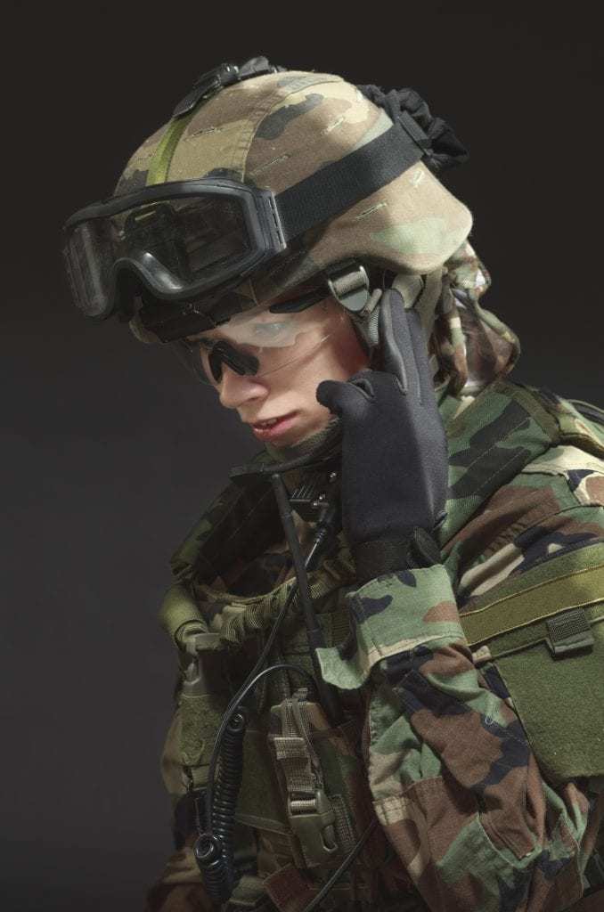 female soldier in full gear holding fingers to ear