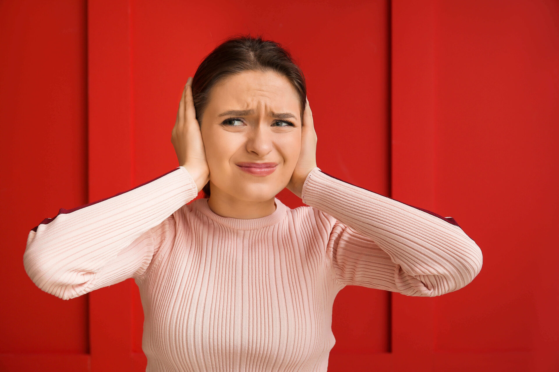 A lady holding her ears because hyperacusis is affecting her